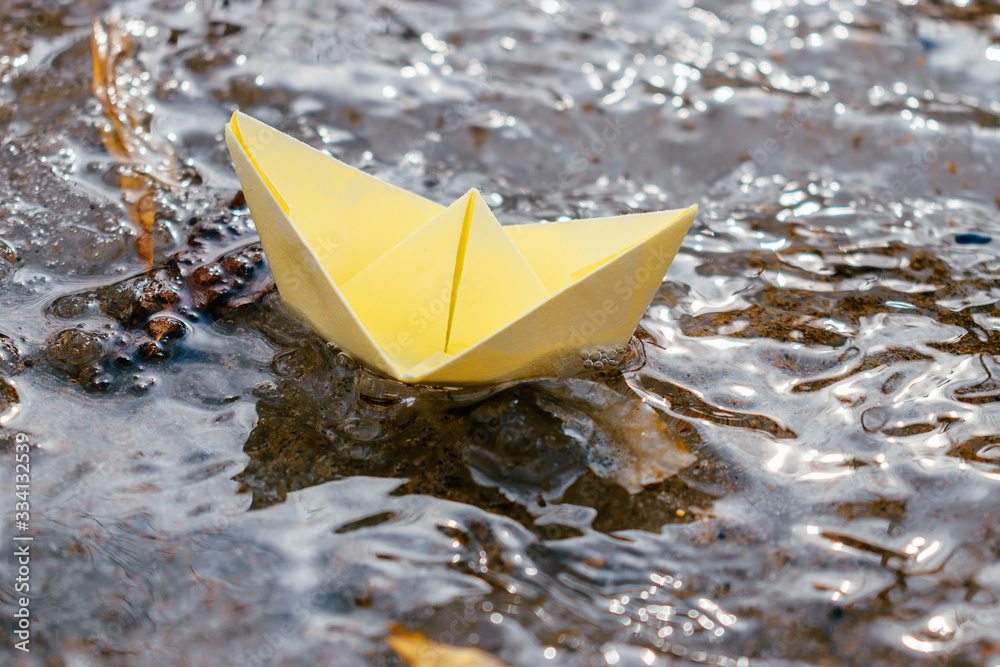 Yellow paper boat sails along the stream. Spring concept.Concept of travel during coronavirus quarantine.Selective focus.