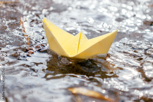 Yellow paper boat sails along the stream. Spring concept.Concept of travel during coronavirus quarantine.Selective focus.