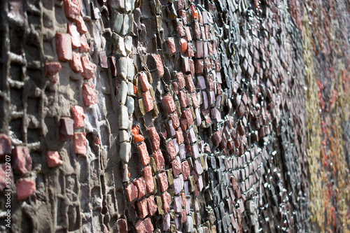 A fragment of a wall with a multicolored mosaic that goes into perspective.Abstract texture,creative background.Selective focus,blurred background.Copy space for text