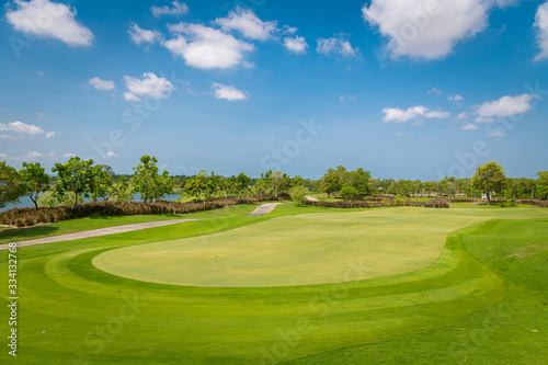 Fototapeta Naklejka Na Ścianę i Meble -  A beautiful view green golf course big tree ,sand bunker and blue cloud sky background.