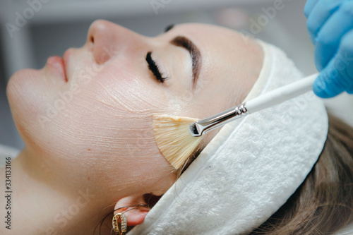 Beauty salon, cosmetician aplying facial peeling mask. Skin treatment concept.