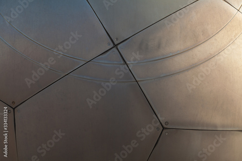 Background image - a fragment of a metal sphere from sheets of titanium joined by rivets