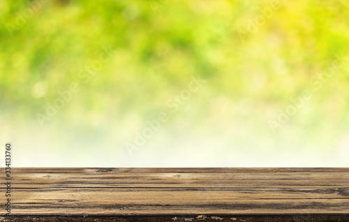 Empty wooden table and blurred green nature background. Natural template with beauty bokeh and warm sunlight. Concept banner for products display
