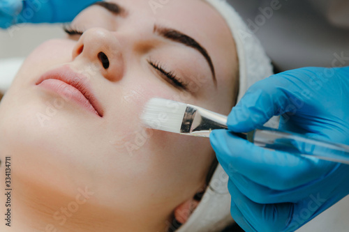 Beauty salon, cosmetician aplying facial peeling mask. Skin treatment concept. photo