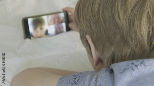 Rear view of a caucasian boy making a video call to his family themes of technology communication video call