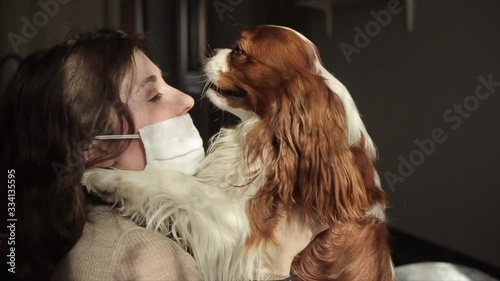 A beautiful young girl in a protective mask hugs and strokes her dog while sitting in quarantine at home.Coronavirus. COVID-19 photo