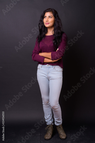 Full body shot of young beautiful Indian woman thinking with arms crossed