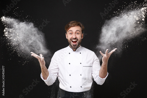 Valokuva Excited funny young bearded male chef cook or baker man in white uniform shirt posing isolated on black background in studio