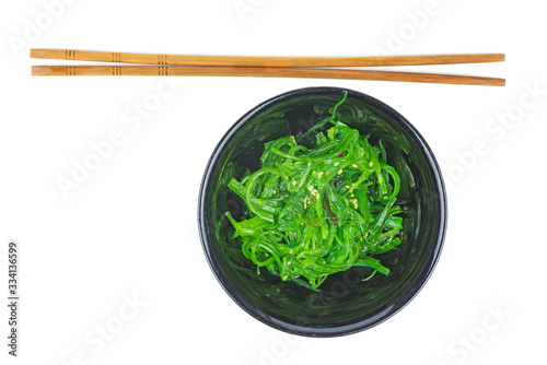 Wakame seaweed in black bowl and chopsticks isolated on white background