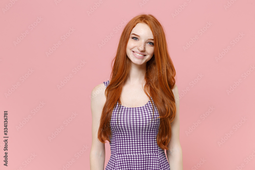 Smiling beautiful young redhead woman girl in plaid dress posing isolated on pastel pink wall background studio portrait. People sincere emotions lifestyle concept. Mock up copy space. Looking camera. Smiling beautiful young redhead woman girl in plaid dress posing isolated on pastel pink wall background studio portrait. People sincere emotions lifestyle concept. Mock up copy space. Looking camera.