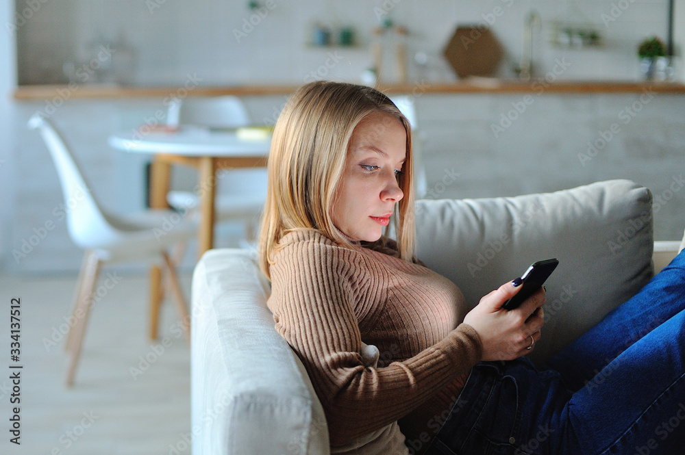 Woman use of smartphone in the evening at home while laying on sofa Woman use of smartphone in the evening at home while laying on sofa