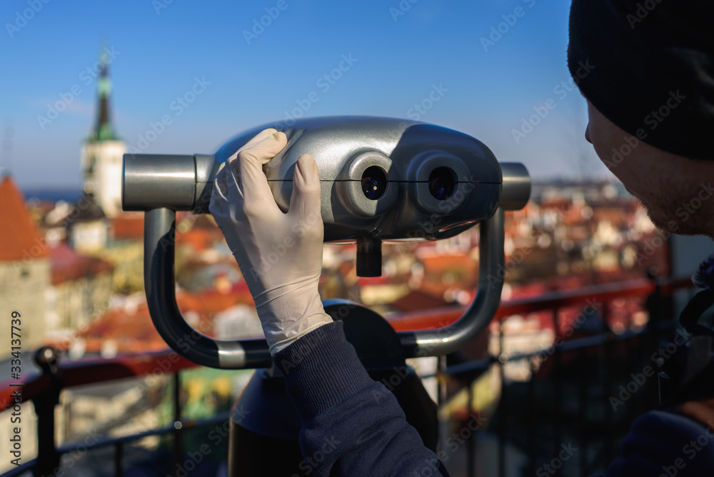Man in latex gloves looking through binoculars