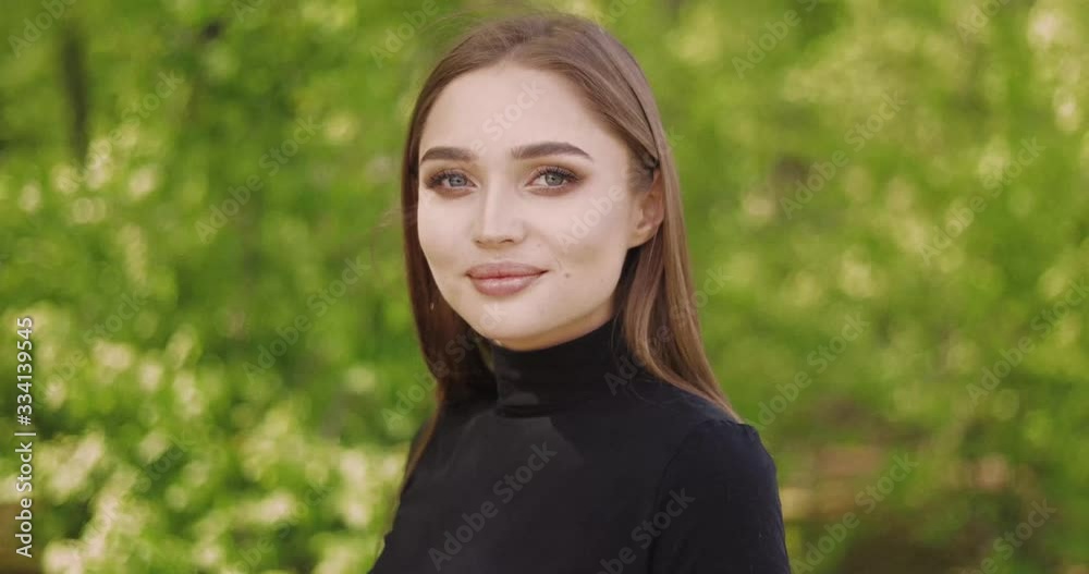 Portrait of young female in black shirt and with long hair looking at camera Portrait of young female in black shirt and with long hair looking at camera