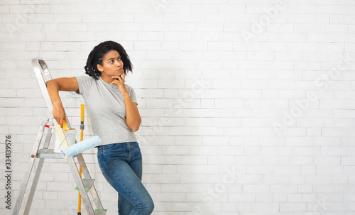 Millennial woman with stepladder thinks about repair
