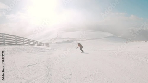 Snowboarder having fun, making turns, going downhill on a slope in ski resorts