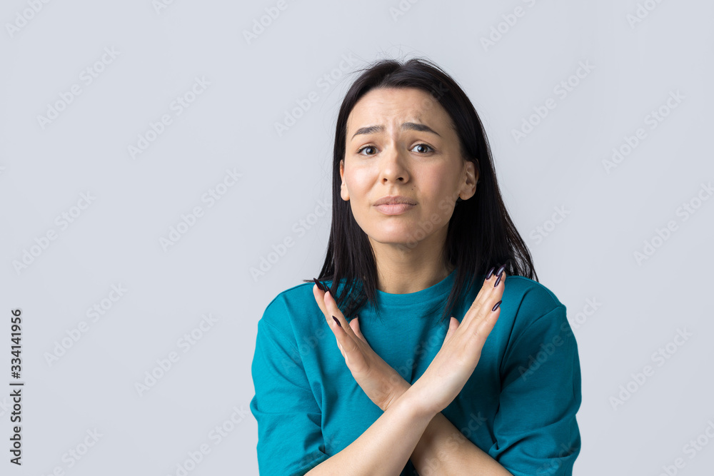 Girl disapproving with no crossing hands sign make negation gesture. Portrait of pretty woman on grey background Girl disapproving with no crossing hands sign make negation gesture. Portrait of pretty woman on grey background