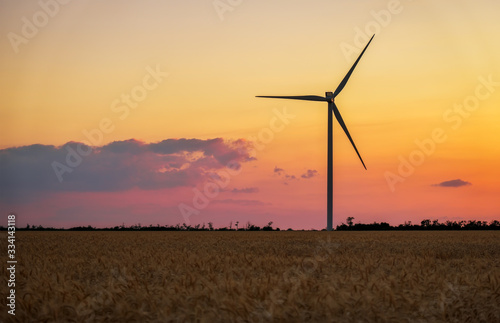 Wind turbines and agricultural field on a summer day. Energy production, clean and renewable energy.