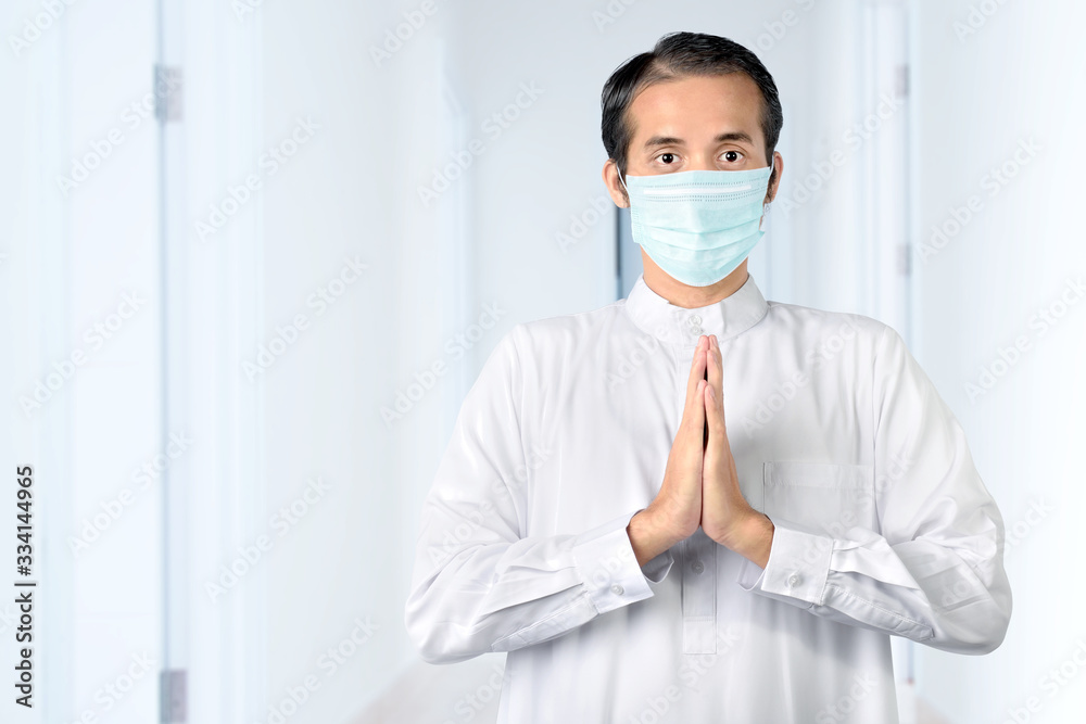 Asian Muslim man wearing flu mask standing and praying Asian Muslim man wearing flu mask standing and praying