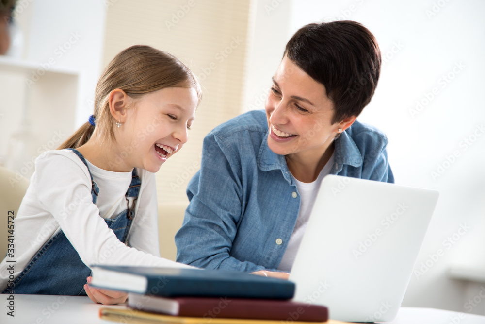 Woman and her little daughter are using a laptop and smiling Woman and her little daughter are using a laptop and smiling