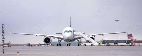 Airport land crew doing flight service for passenger airplane, before the flight departure. Wide panorama view.