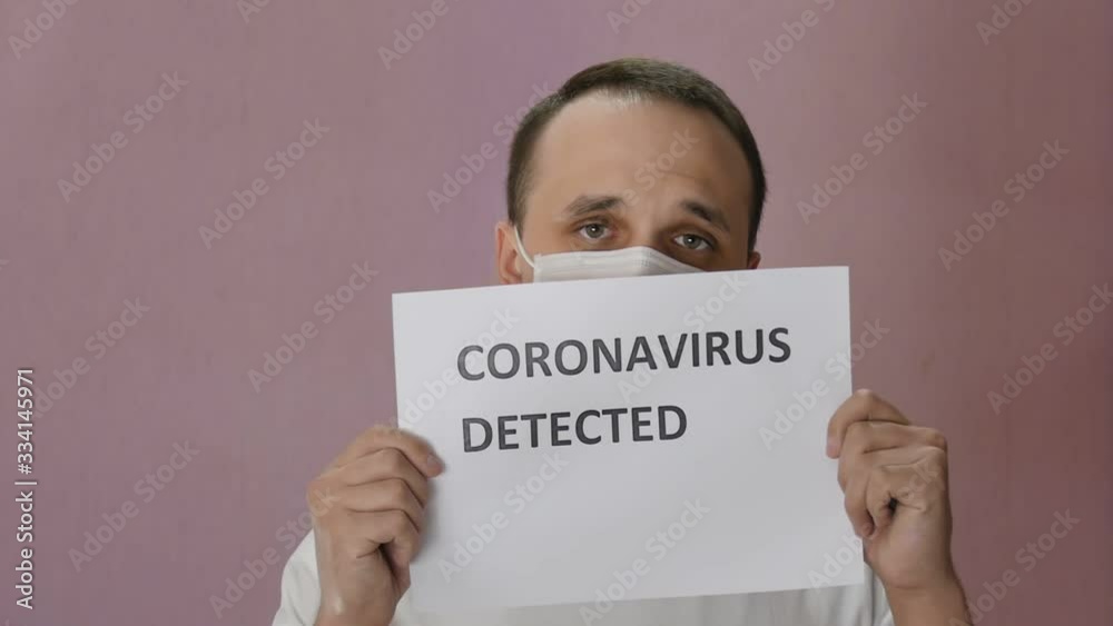 Sad man in mask against covid-19, looks at camera and holding a poster. Coronovirus detected. Pandemic. Global spread of coronavirus. Epidemic precautions. Acute Respiratory Sad man in mask against covid-19, looks at camera and holding a poster. Coronovirus detected. Pandemic. Global spread of coronavirus. Epidemic precautions. Acute Respiratory