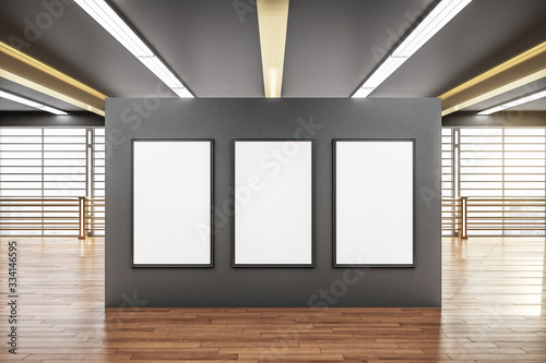 Three blank poster on gray wall in modern spacious hall