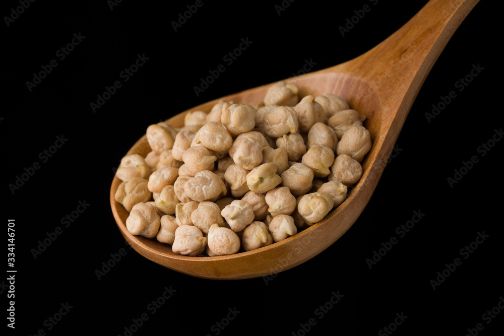Chickpeas in a wooden spoon on a black background. Close up , macro Chickpeas in a wooden spoon on a black background. Close up , macro