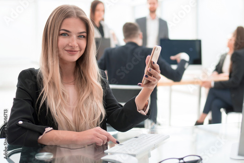 business woman with a smartphone sitting at a Desk