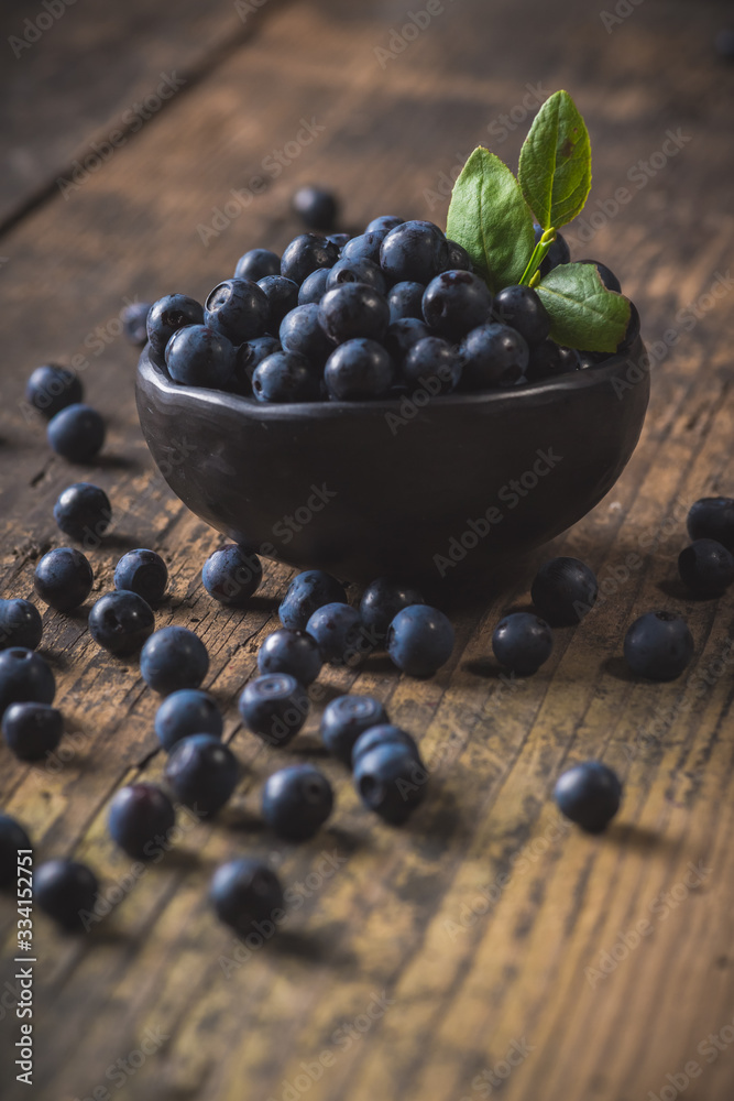 Clay bowl with organic, wild forest blueberries on a rustic wooden table. Clay bowl with organic, wild forest blueberries on a rustic wooden table.