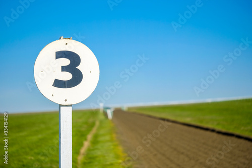 3 furlong distance marker seen on the edge of a professional flat-racing training track in the UK. The track extends to the distance before curving to the right up an incline.