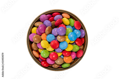 Colorful candies in a wooden bowl case isolated on wood background photo