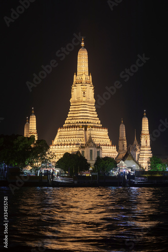Arun Temple  one of the most famous in Bangkok  Taliandia  stands up  illuminated at night  on the banks of the Chao Phraya River with its troubled waters.