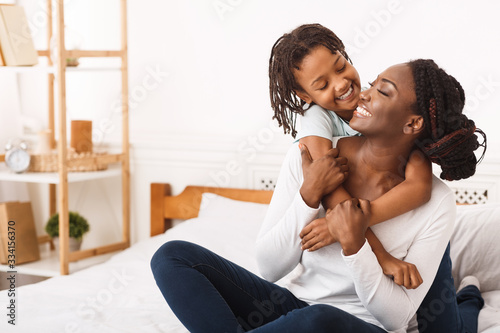 Black girl embracing her mom at home