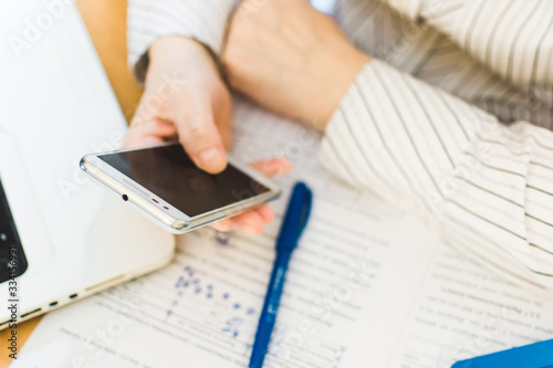 Social distancing protect coronavirus or covid-19. Closeup woman using white mobile phone. Female working in workplace at home. Teacher teaches remotely. Online education and distance work concept.