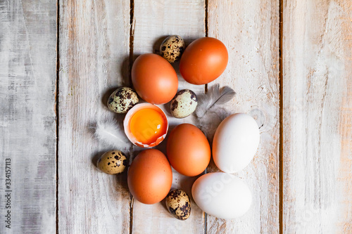 Composition with raw chicken and quail eggs on wooden rustic background. Preparation for traditional Easter family dinner at home. Concept of domestic household. Copy space, macro, top view, flat lay