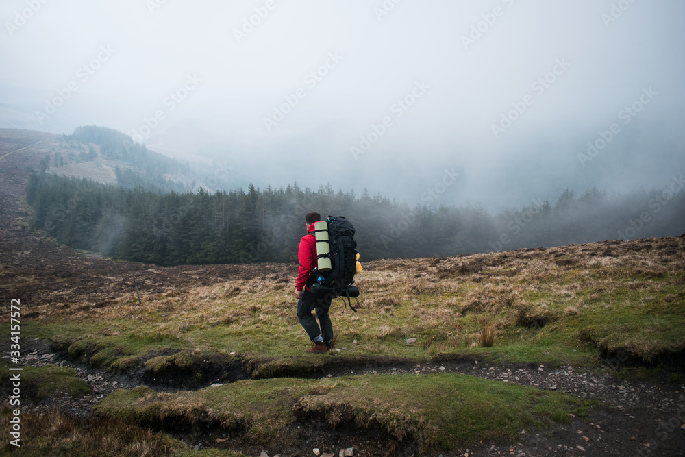 Senderista caminando por el monte en un día con niebla y árboles al fondo Senderista caminando por el monte en un día con niebla y árboles al fondo