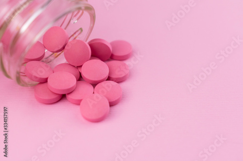  Pink pills snapped from a vial isolated on a pink background. Copy space.