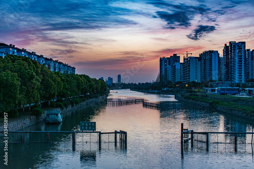 River through Kunshan, China at sunset with skyscraper apartments on the horizon photo