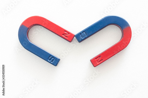 Two horseshoe magnets attracting each other on a white background.
