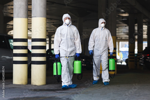 Men in coronavirus suits holding disinfection chemicals outdoor photo