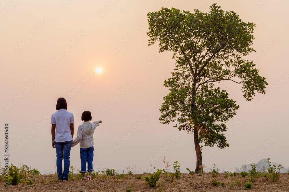 silhouette of two children standing on mountain at sunset background silhouette of two children standing on mountain at sunset background
