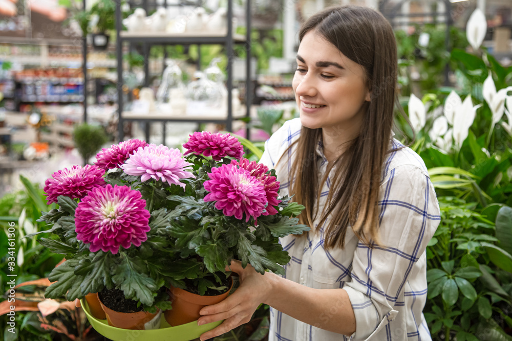 Beautiful young woman in a flower shop and choosing flowers.
