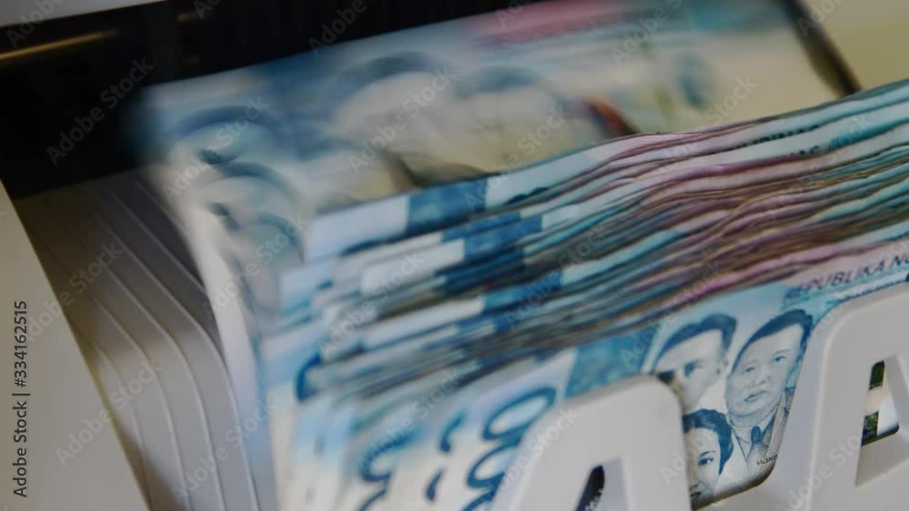 Money counting machine ejecting Philippine peso cash