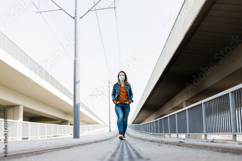 Young woman with a surgical mask in an empty tram station