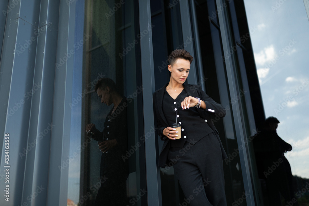 Female in office suit made an appointment and is waiting for colleague and drinks coffee Female in office suit made an appointment and is waiting for colleague and drinks coffee