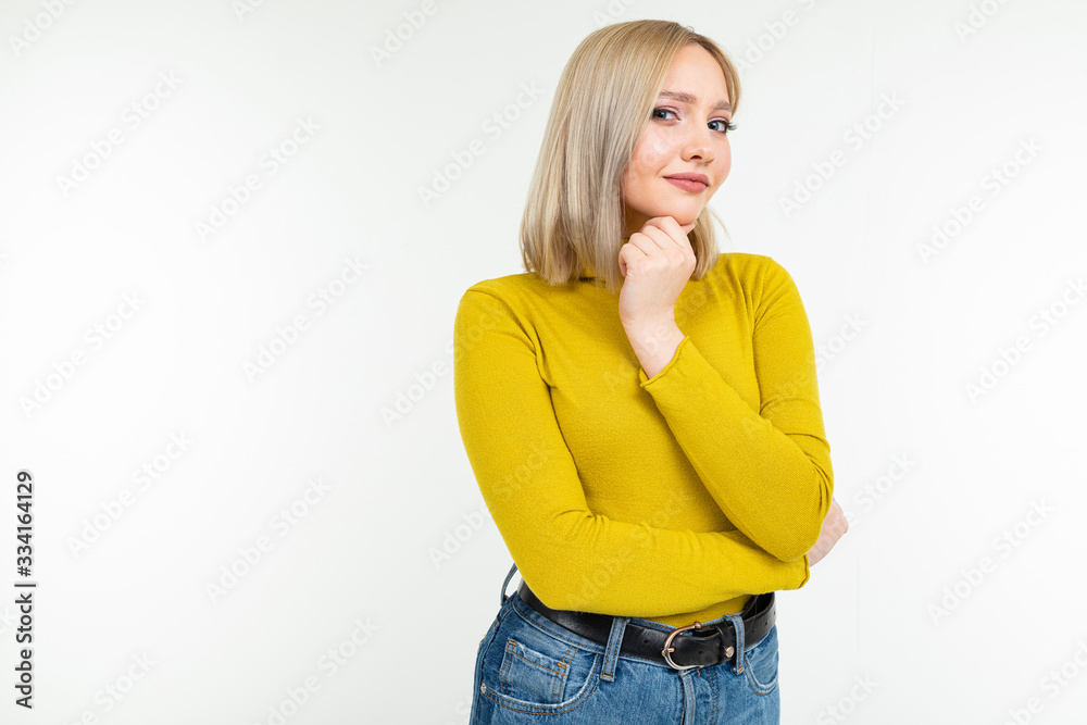 girl in a yellow blouse and jeans looks thoughtfully at a white studio background girl in a yellow blouse and jeans looks thoughtfully at a white studio background