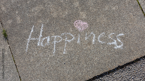 Starnberg, Bavaria / Germany - Mar 27, 2020: Word Happiness written on pavement with white chalk. With pink heart as dot for the i. Concept for postitive thinking, feeling happy, good vibrations. photo