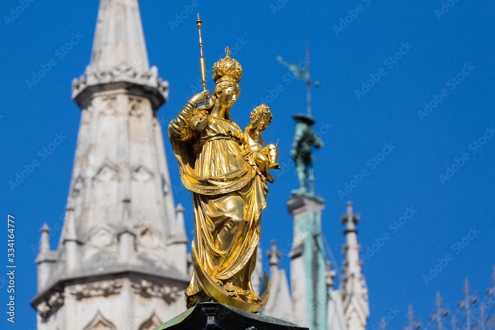Munich, Bavaria / Germany - Mar 18, 2020: Close up of Marienstatue at the Marienplatz (Mary's Square). A golden colored statue of the Holy Virgin Mary. Erected in 1638 by Duke Elector Maximilian I.