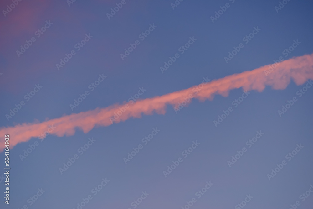 Engine exhaust contrails in the sky at sunset.