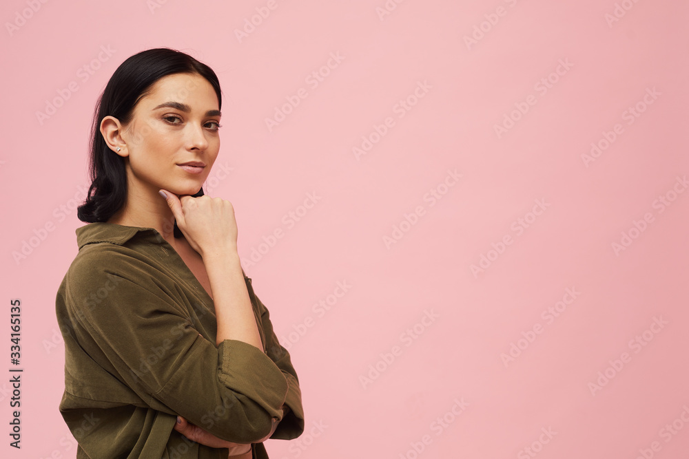 Waist up portrait of modern young woman posing confidently and looking at camera while standing against pink background in studio, copy space Waist up portrait of modern young woman posing confidently and looking at camera while standing against pink background in studio, copy space